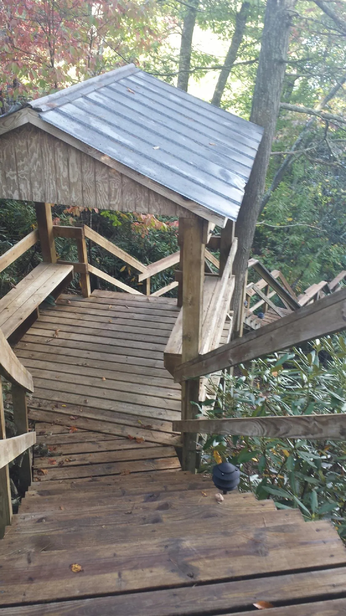 Metal roofed shelter over wooden steps on a wooded walkway — Skylight Repair & Installation work by our crew in Hebron